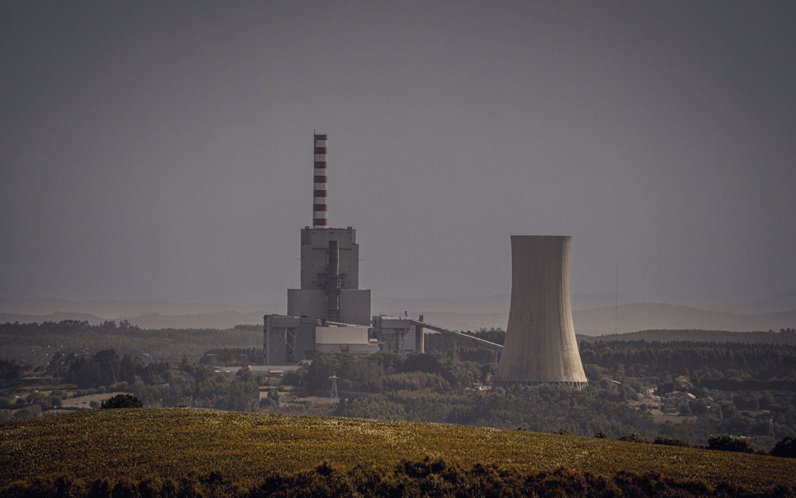 A power station cooling tower against a hillside