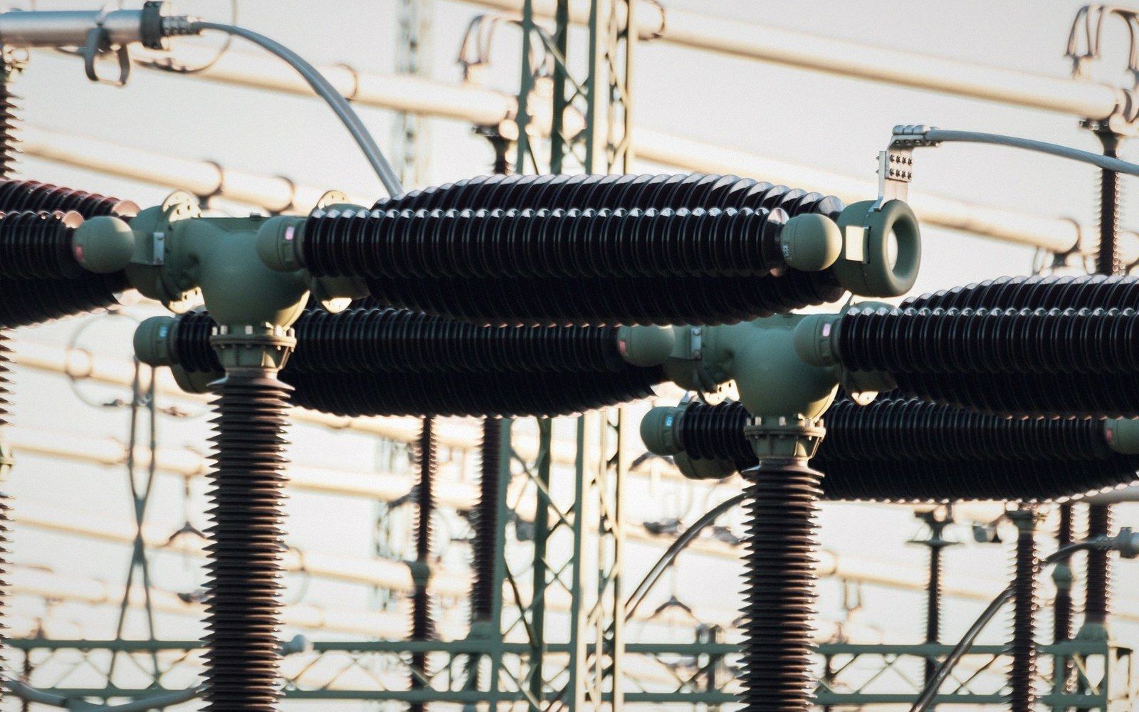 Ribbed insulators and conductors form curved bushings at an electrical substation