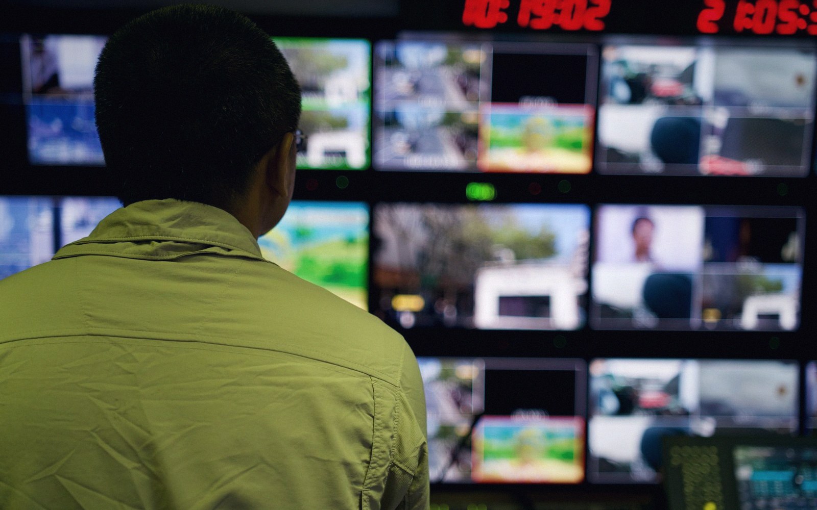 A technician watches a wall of monitors displaying live broadcast feeds in a control room