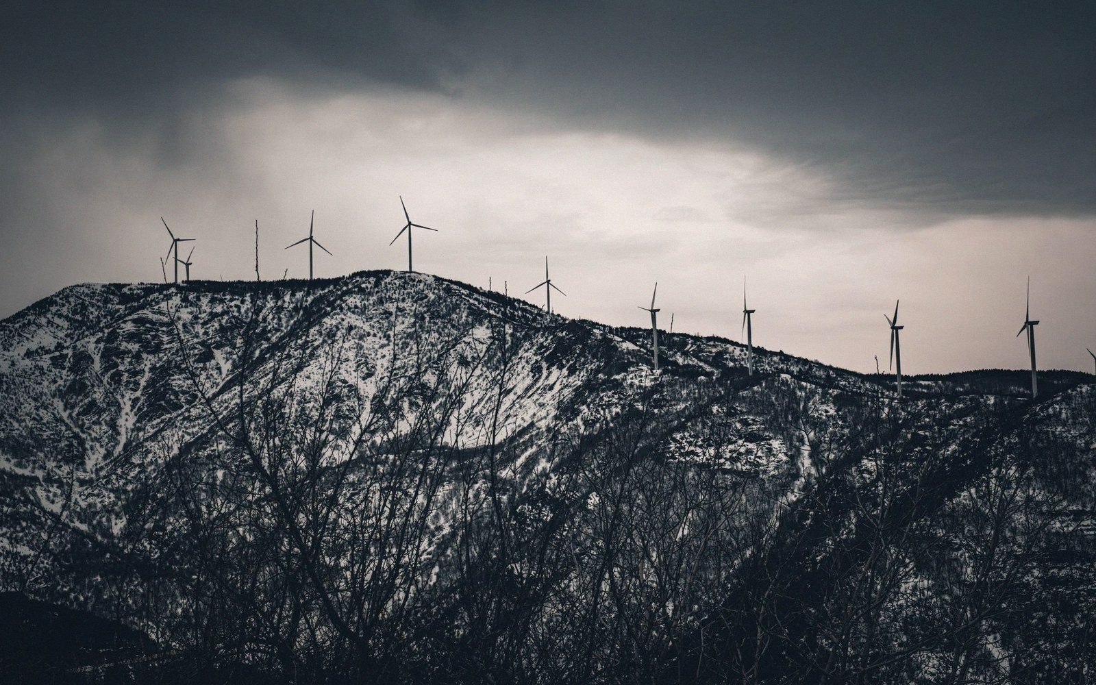 Wind turbines along an exposed ridge under overcast sky